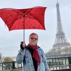 Johnny Paris with his red umbrella in front of the Eiffel Tower